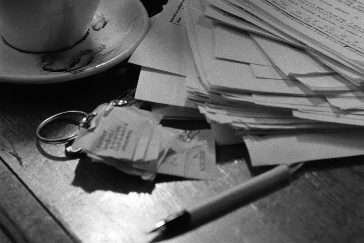 Escritorio de una inmobiliaria: un llavero con etiquetas de papel, una pila de contratos impresos, una lapicera y una taza de café